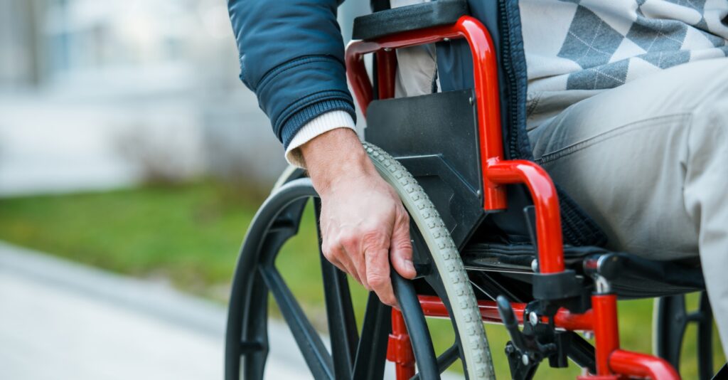 Closeup of a person with his hands on the wheel of a wheelchair