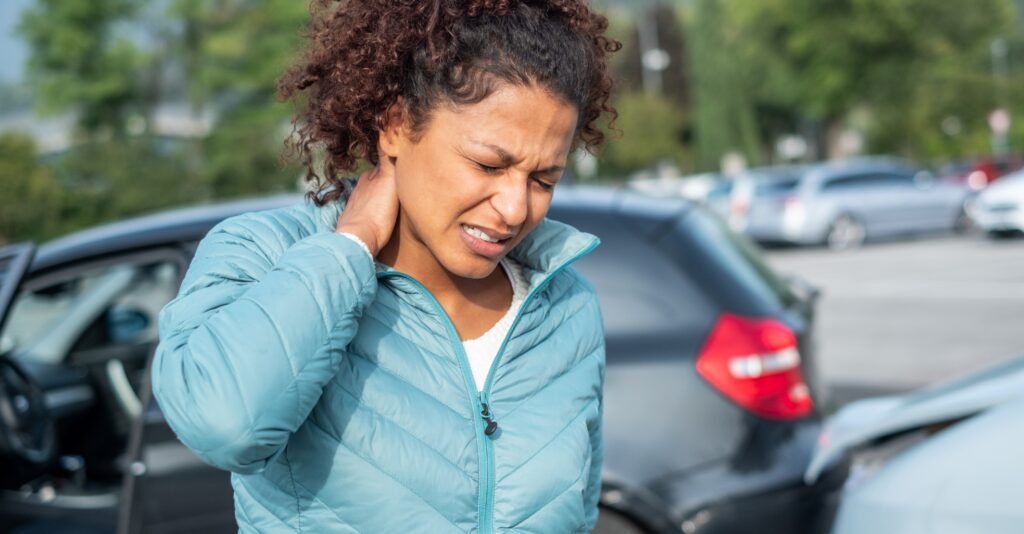 A woman experiencing neck pain at the scene of a car accident