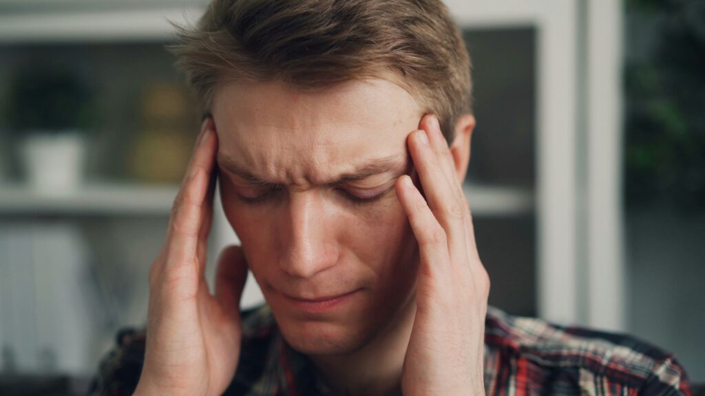 A man with his hands on his head, appearing contemplative or stressed.