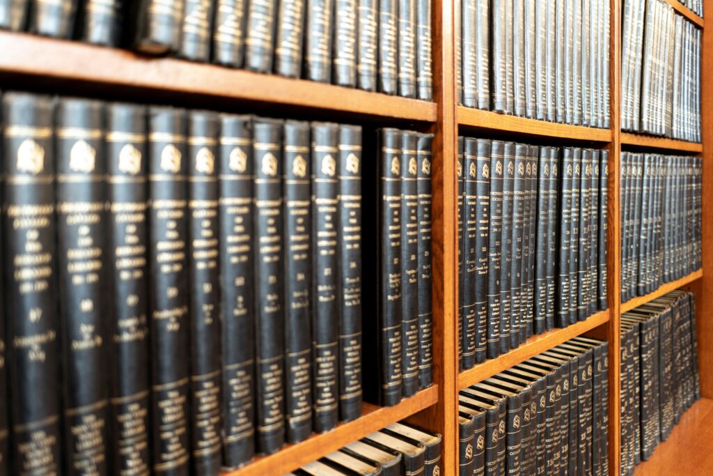 Rows of hardcover legal books lined up on wooden shelves in a law library, with gold lettering visible on the spines.