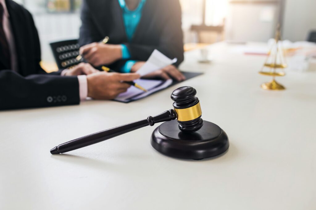 Business professionals in suits seated at a table with a judge's gavel, discussing legal matters.