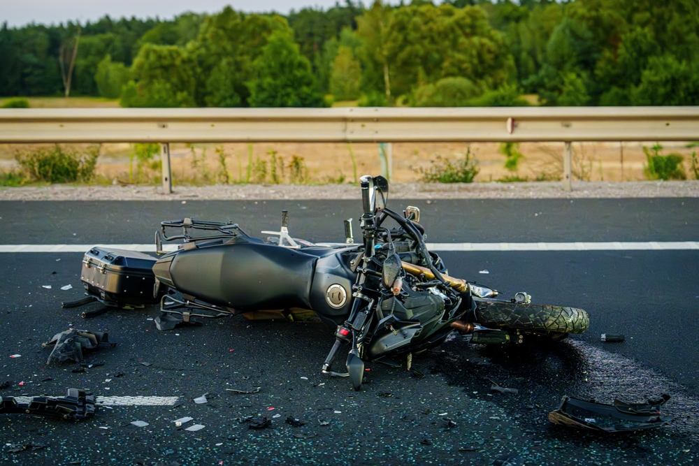 A motorcycle lies on its side on the road, indicating a motorcycle accident has occurred.