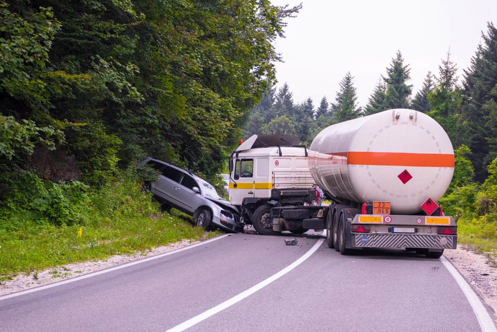 A truck and a car collide on a road, resulting in a significant accident scene.