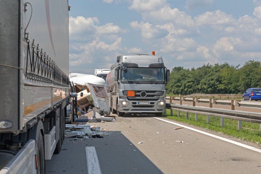 A truck drives down the road, involved in an accident, with debris scattered around.